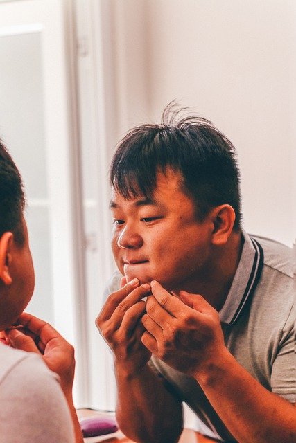 man inspecting acne in a mirror