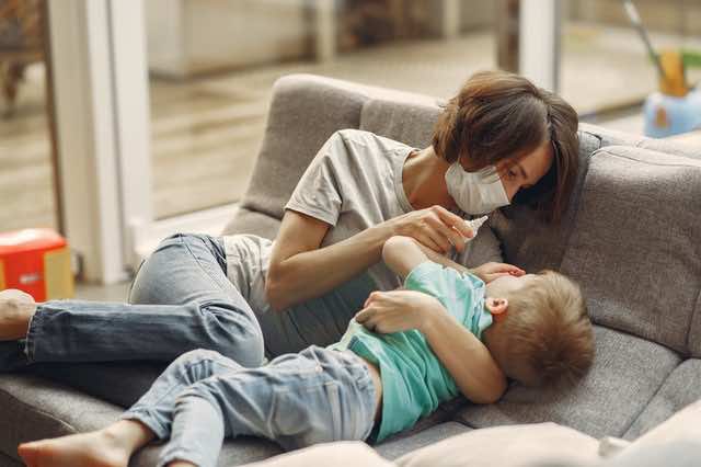 Mother and son on a sofa with a nasal spray in the mother's hand.